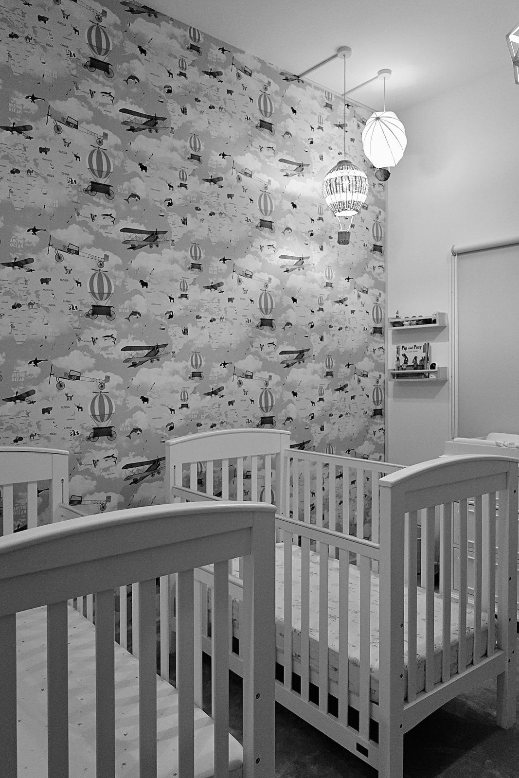 Twin cribs against patterned wallpaper